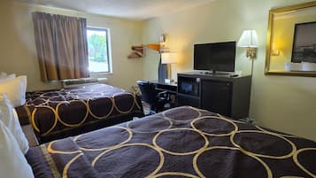 A hotel room with two beds, a desk with a TV, a lamp, and a window with curtains.