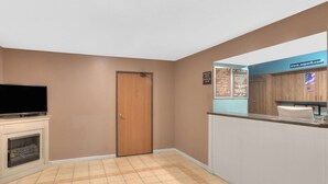 Ein Empfangsbereich mit Holztür, einem Fernseher auf dem Kaminvorsatz und einer Rezeption mit Schild für www.super8.com.