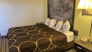Une chambre d’hôtel avec un lit, une table de chevet avec une lampe et un téléphone.
