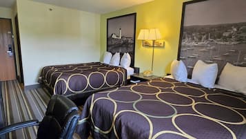 A hotel room with two beds, a desk, a chair, a lamp, and a wall-mounted phone.