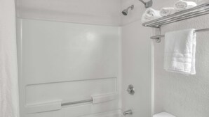Ein Badezimmer mit Dusche, Toilette und Handtuchhalter mit Handtüchern.