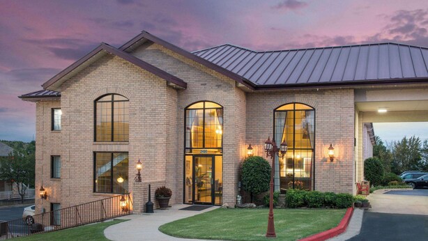 A two-story brick building with large windows and a well-maintained lawn. - Super 8 by Wyndham Branson/Andy Williams Theater (Branson)