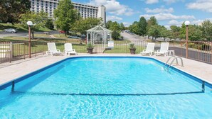 A rectangular swimming pool with clear blue water, surrounded by a metal fence, and white lounge chairs. - Super 8 by Wyndham Branson/Andy Williams Theater (Branson)