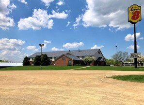 A two-story building with a brick facade and a sloped roof, surrounded by a well-maintained lawn and a clear sky.