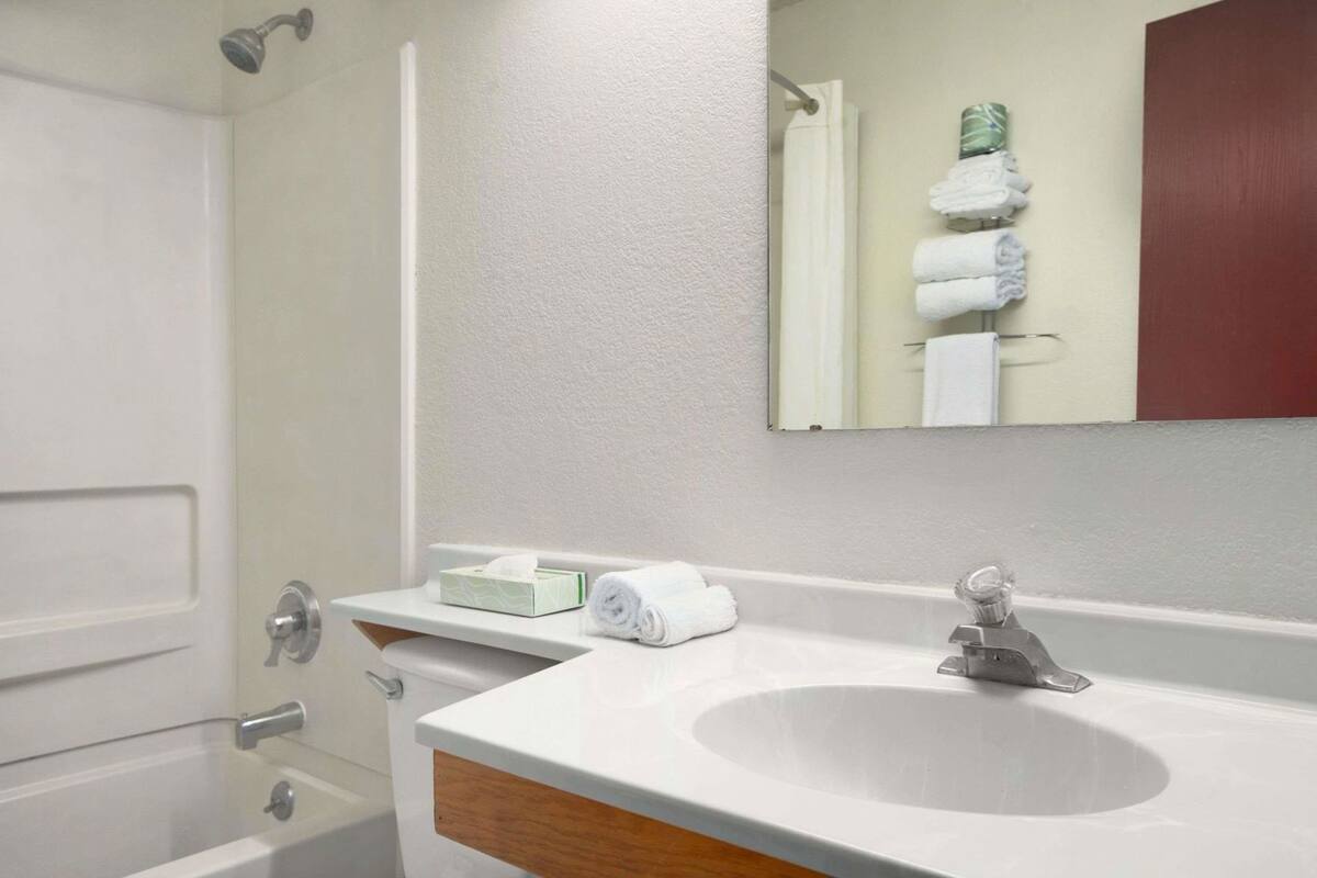 A bathroom with a white sink, a mirror, a towel rack with towels, and a toilet.