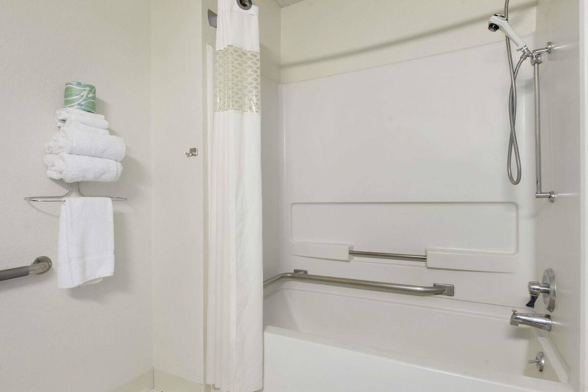 A bathroom with a bathtub, a shower, and a towel rack with folded towels.