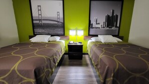 Une chambre d’hôtel avec deux lits, des murs verts et deux tableaux représentant des ponts.