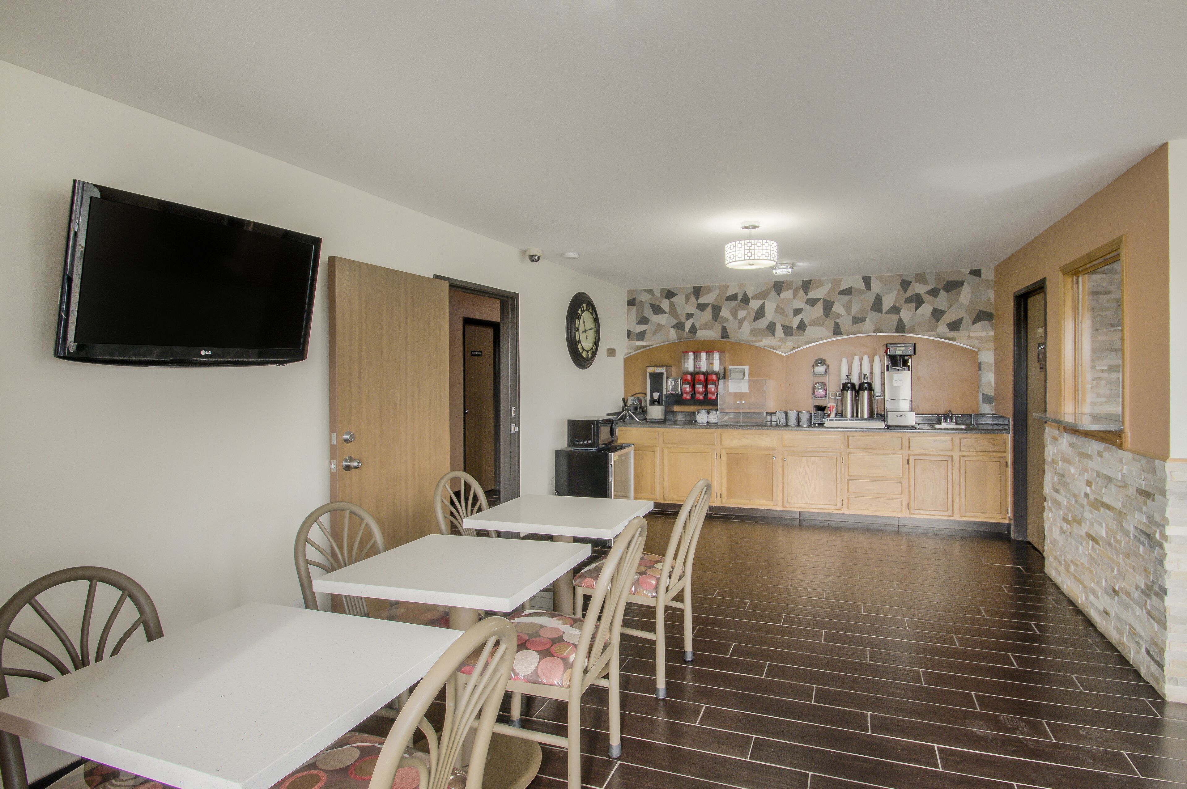 Una cucina moderna con televisione a schermo piatto, mobili in legno e angolo caffè.