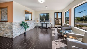 A modern interior with a stone accent wall, a glass table, and seating area with a view. - Americas Best Value Inn & Suites Harrisonville (Harrisonville)