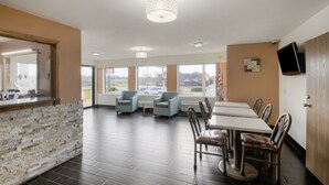 A restaurant with a stone counter, multiple tables, chairs, and large windows offering a view of the outside. - Americas Best Value Inn & Suites Harrisonville (Harrisonville)