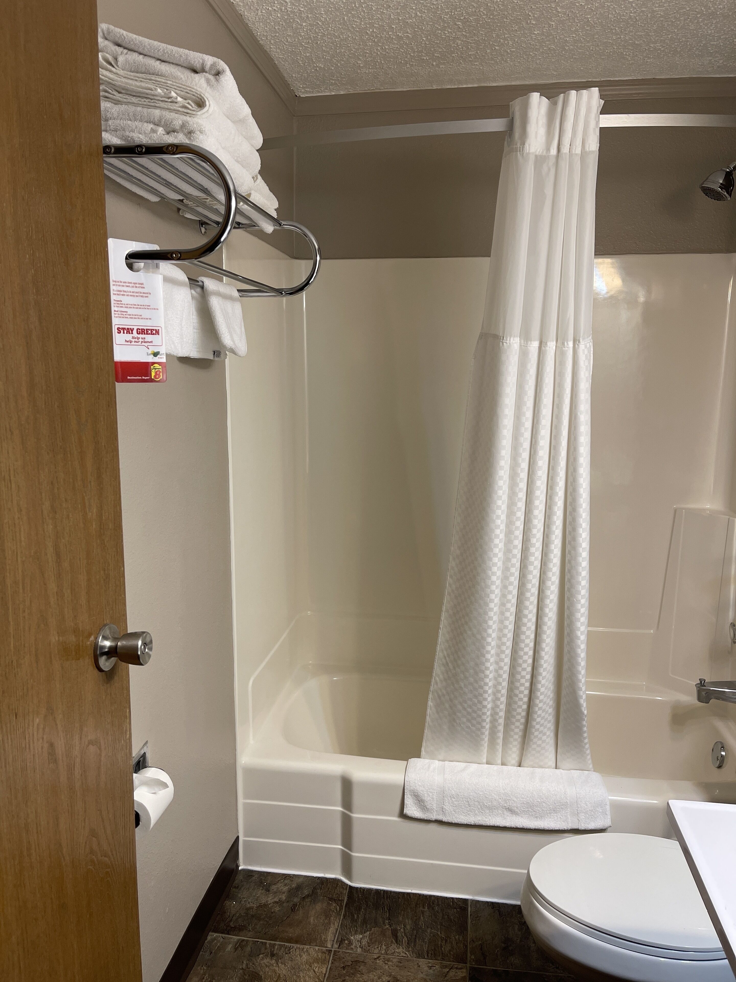 A bathroom with a shower, toilet, and a towel rack with towels.