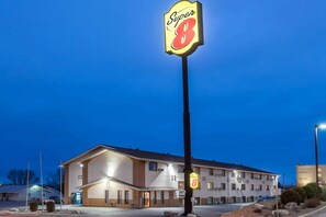 A motel with a prominent 'Super 8' sign, a single-story building with a flat roof, and a parking lot. - Super 8 by Wyndham Bismarck (Bismarck)