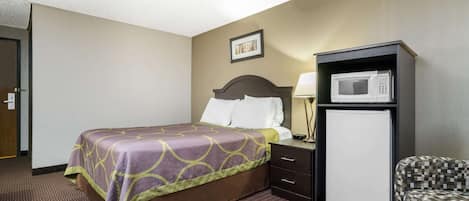 Une chambre d’hôtel avec un lit, un bureau doté d’un micro-ondes, une chaise et une porte.