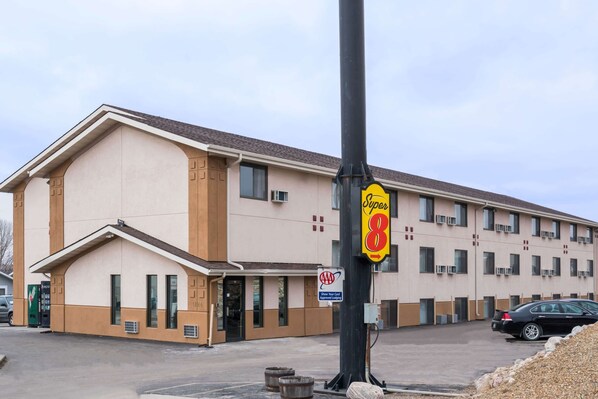 A Super 8 motel with a beige exterior, multiple windows, and a parking lot. - Super 8 by Wyndham Bismarck (Bismarck)