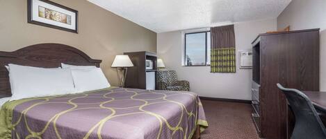A hotel room with a large bed, a desk, a chair, a lamp, a picture on the wall, and a window with curtains.