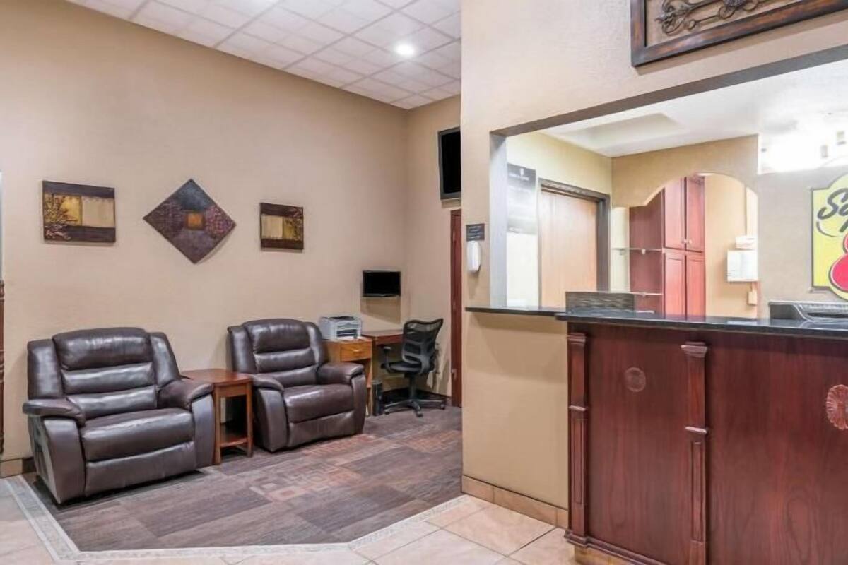 A hotel lobby with leather chairs, a reception desk, and a sign for 'Super 8'.