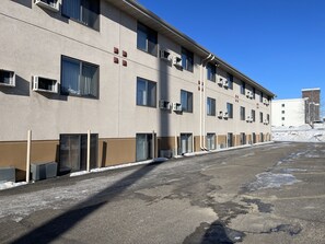 A multi-story building with a flat facade, air conditioning units, and a parking area with snow. - Super 8 by Wyndham Bismarck (Bismarck)