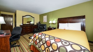 Habitación de hotel con cama, escritorio con teléfono, silla, cómoda y espejo.