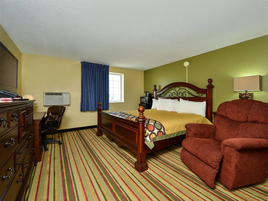 Ein Hotelzimmer mit Bett, Stuhl, Kommode und Fernseher.