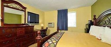 A hotel room with a wooden bed, a dresser, a television, and a window with curtains.