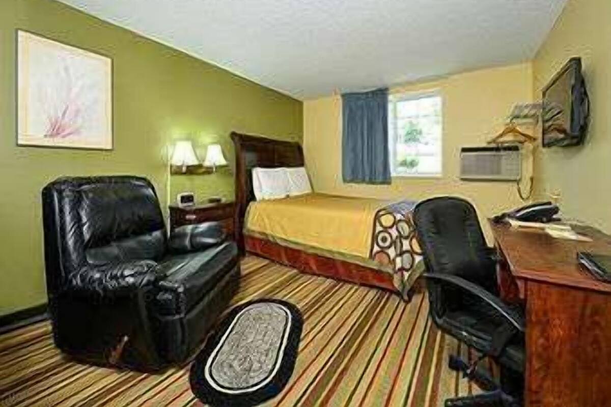 Una habitación de hotel con cama, escritorio, silla, sofá y ventana.