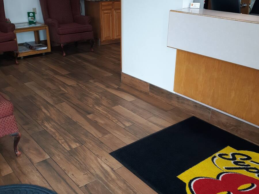 Un área de recepción con piso de madera, un mostrador y una silla.