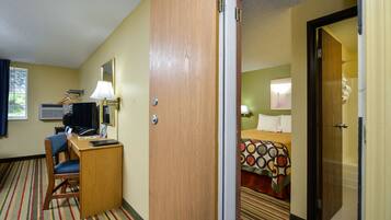 A hotel room with a desk, chair, bed, and a bathroom visible through an open door.