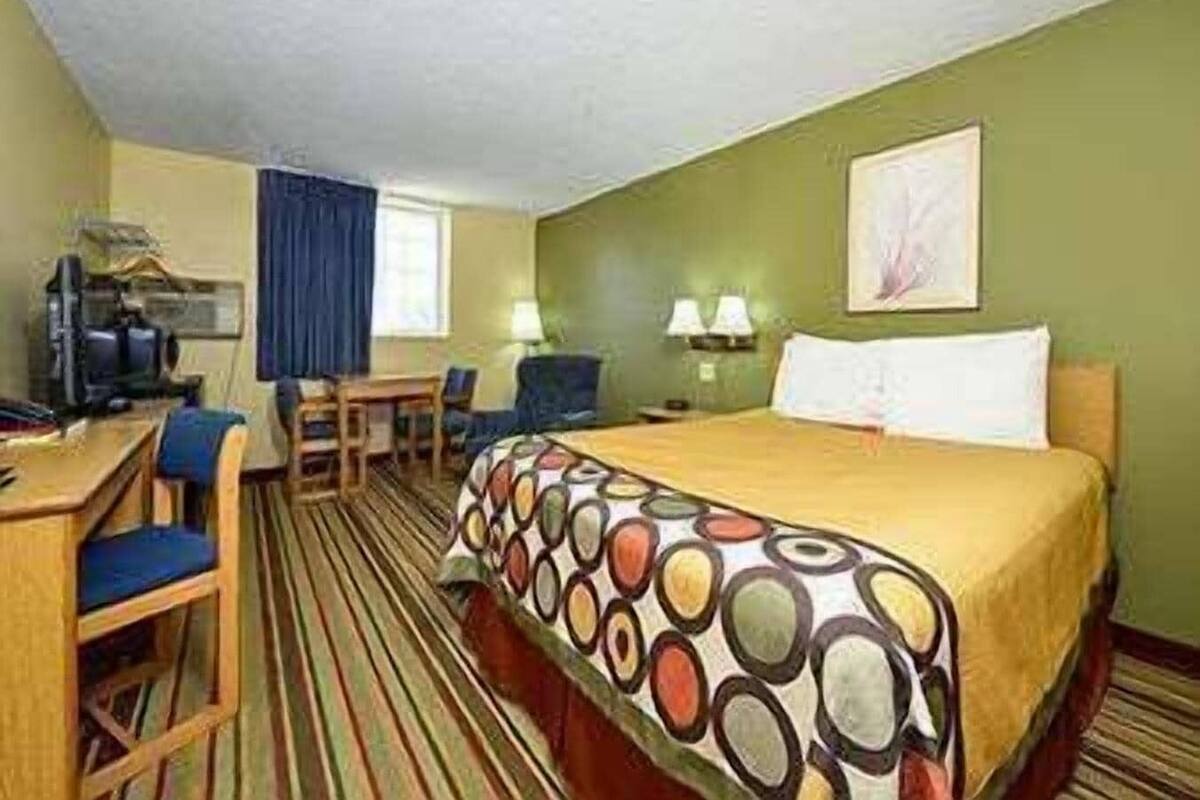 Una habitación de hotel con cama, escritorio, silla y televisor.