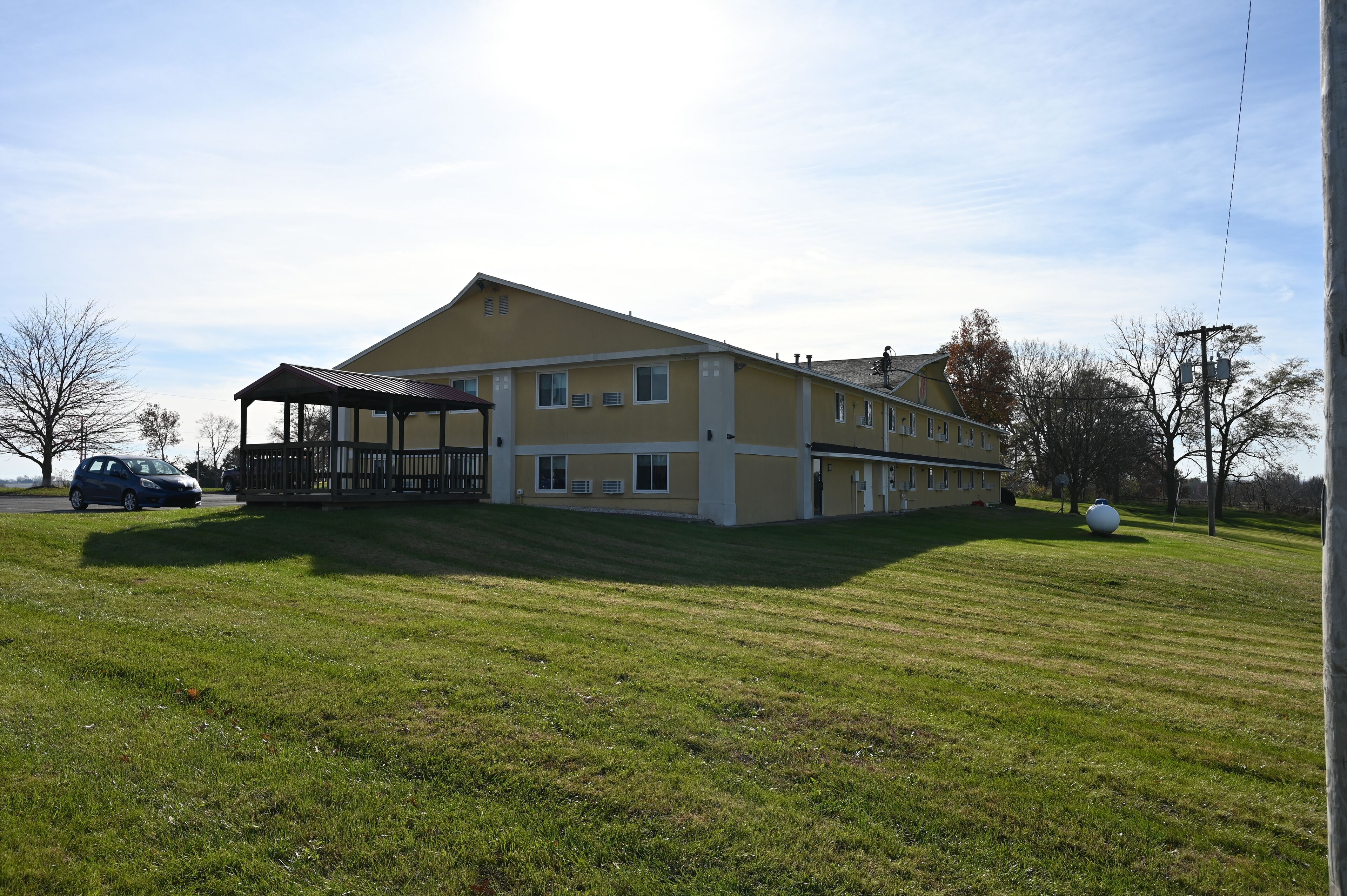 A two-story building with a covered porch and a grassy lawn.
