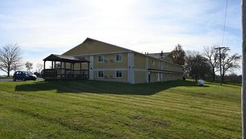 A two-story building with a covered porch and a grassy lawn.