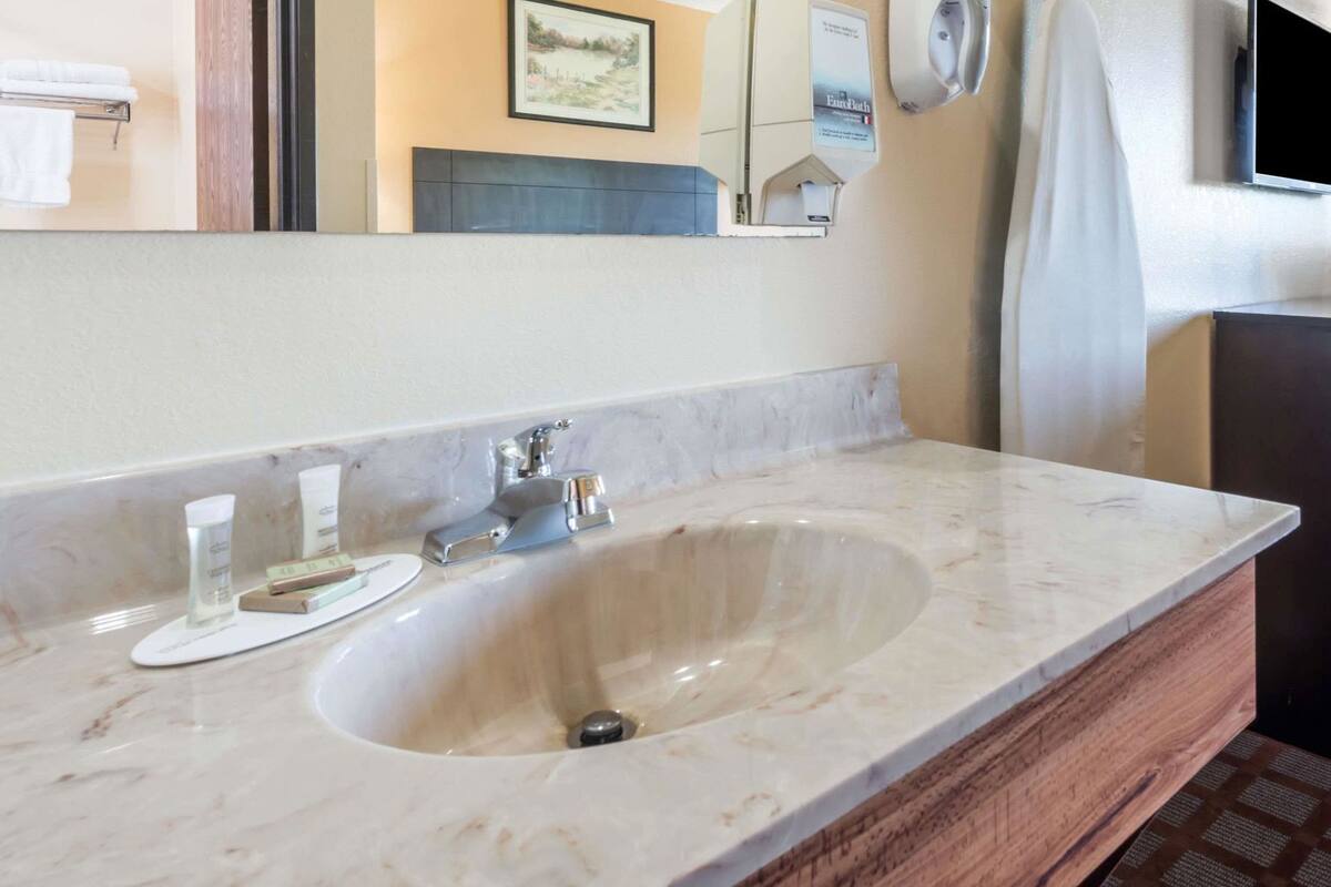 A bathroom with a marble sink, a mirror, and a towel rack.