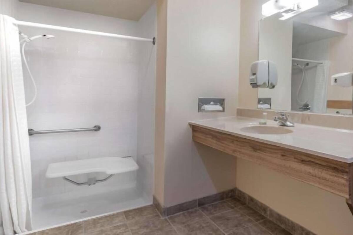 A bathroom with a shower, a sink, a mirror, and a towel rack.