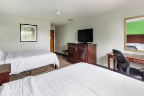 A hotel room with two beds, a desk, a chair, a television, and a framed picture on the wall.