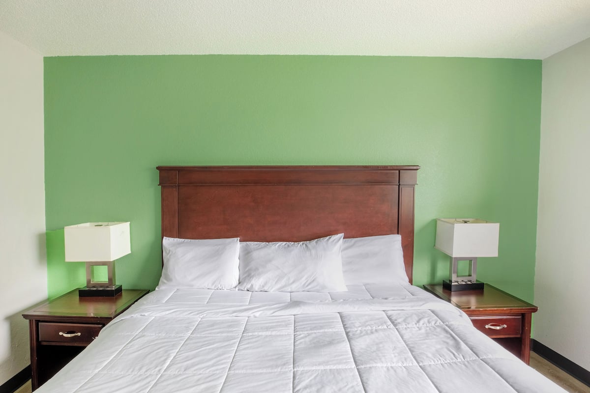 A hotel room with a large bed, two bedside tables, and green walls.