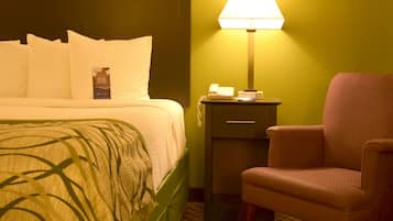 Une chambre d’hôtel avec un lit, une table de chevet, une lampe et une chaise.