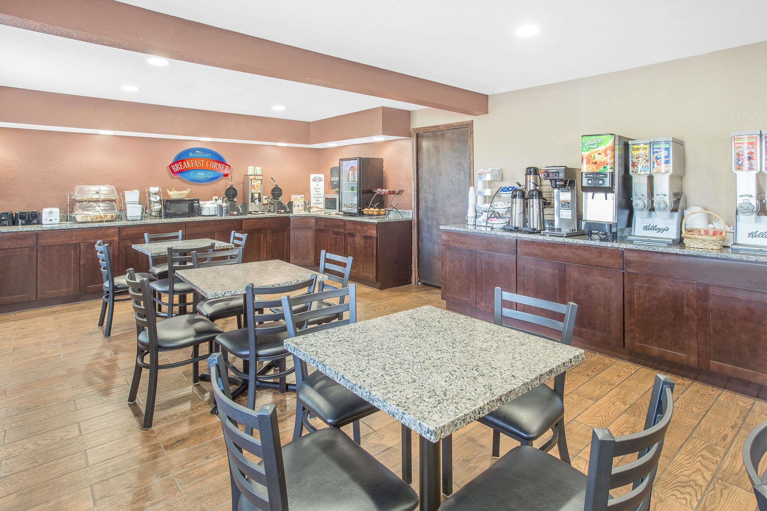 Un comedor con mesas y sillas, una cafetera y un refrigerador.