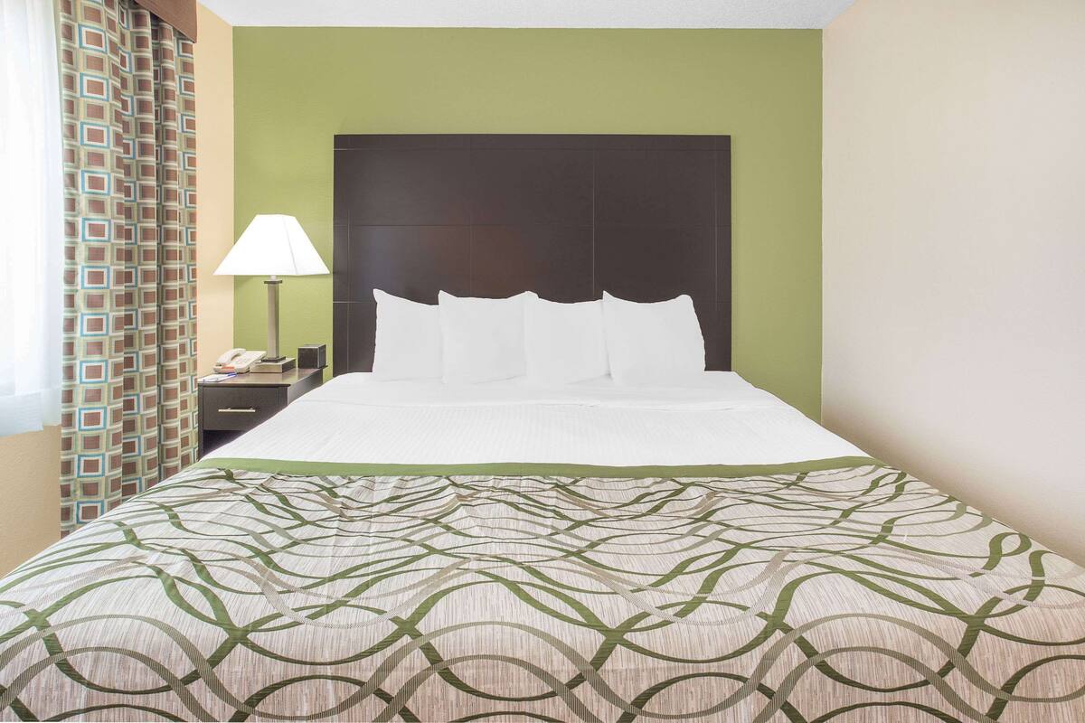 Une chambre d’hôtel avec un grand lit, une table de chevet avec une lampe et une couvre-lit à motifs.