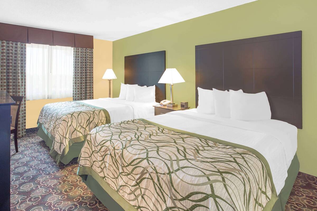Une chambre d’hôtel avec deux lits, un bureau et une chaise.