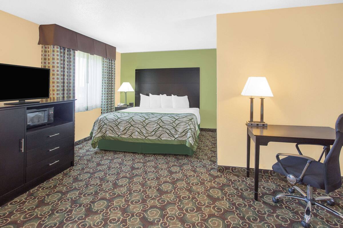 Une chambre d’hôtel avec un lit, un bureau, une chaise, une télévision et une lampe.