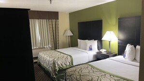 Een hotelkamer met twee bedden, een bureau, een lamp en een raam met gordijnen.