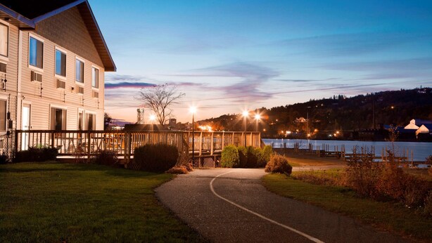 A modern building with a wooden deck and a pathway leading to a body of water.