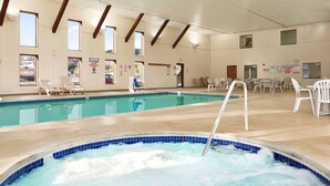 An indoor swimming pool with a hot tub, lounge chairs, and a sunroof.