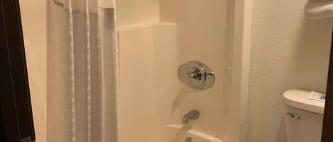 A bathroom with a bathtub, toilet, and shower curtain.