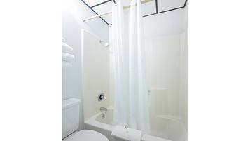 Een badkamer met een bad, toilet en een douchegordijn.