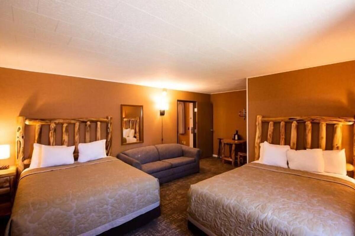 Une chambre d’hôtel avec deux lits, un canapé, une petite table et un miroir.