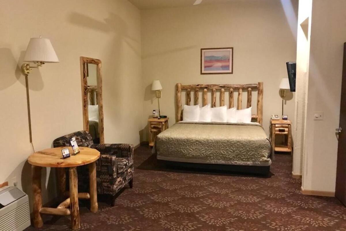 Une chambre d’hôtel avec un lit, une petite table ronde, une chaise, un miroir et deux lampes de chevet.
