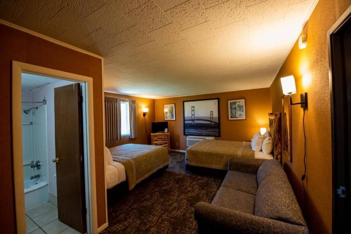 Une chambre d’hôtel avec deux lits, un canapé, une salle de bain et une vue sur le Golden Gate Bridge.