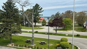 A parking lot with picnic tables, a bridge in the background, and a clear sky.