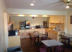 A small, cozy cafe with wooden furniture, a coffee machine, and a microwave. - Super 8 by Wyndham Bridgeview of Mackinaw City (Mackinaw City)