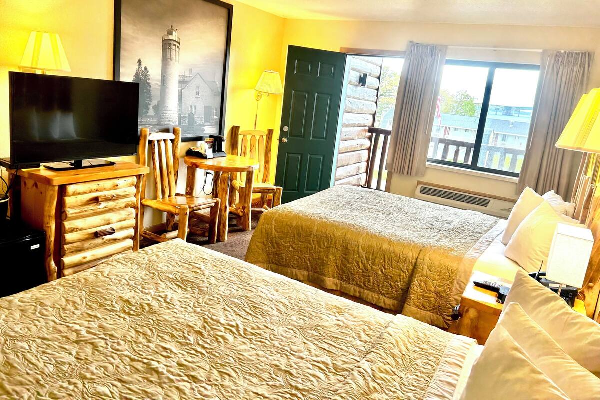 Une chambre d’hôtel avec un grand lit, un bureau avec une chaise, une télévision et une fenêtre avec des rideaux.